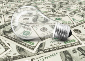 light bulb on top of many 100 dollar bills