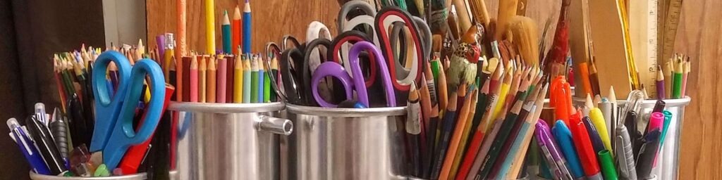 art supplies pens pencils scissors in metal containers on table
