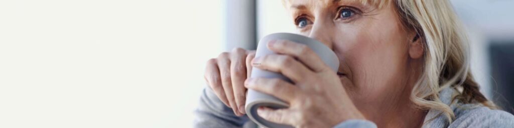 empty nester mom sitting by window drinking coffee