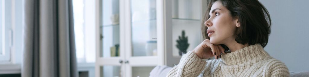 woman sitting on couch thinking about what to do now that kids are gone